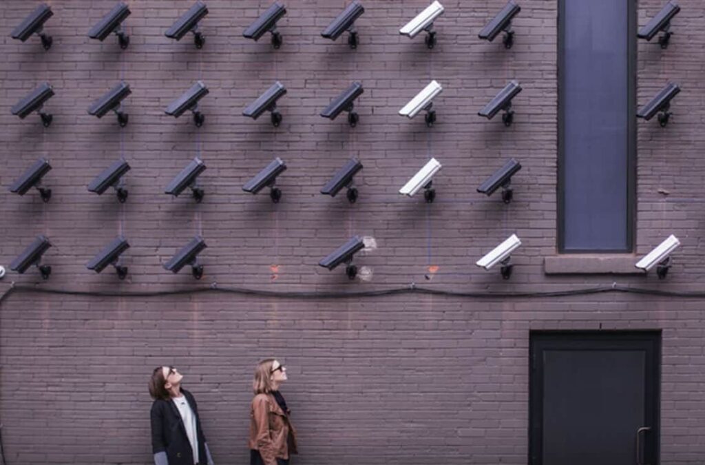 Two women looking up at a wall full of security cameras